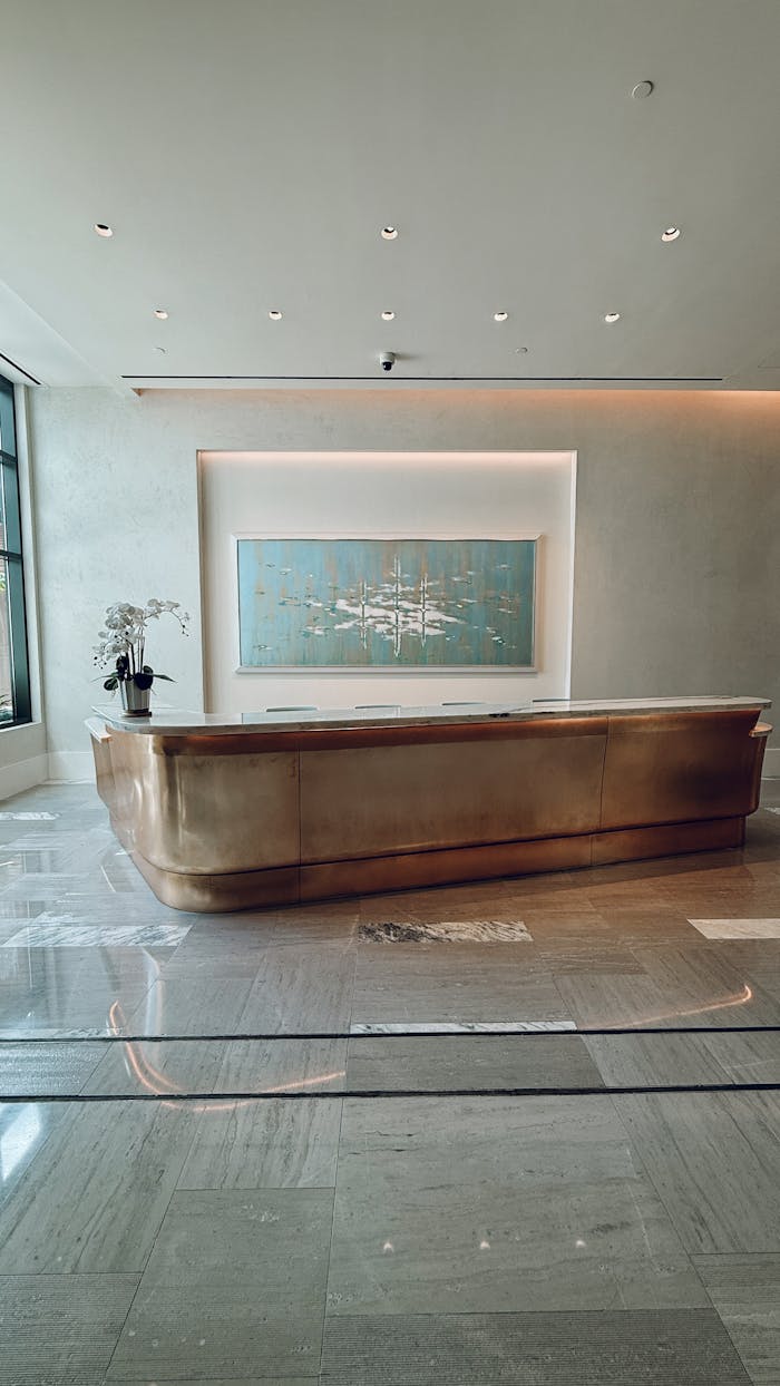 Modern hotel lobby featuring a striking gold reception desk and contemporary artwork.
