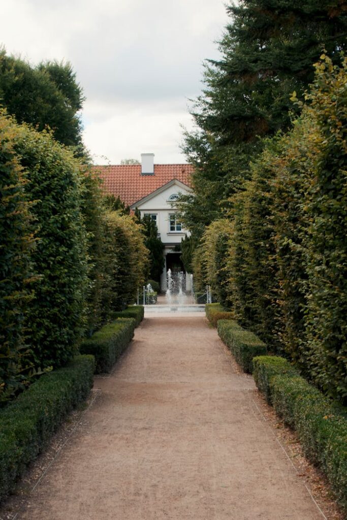 Lush greenery frames a serene pathway leading to a classic estate house.