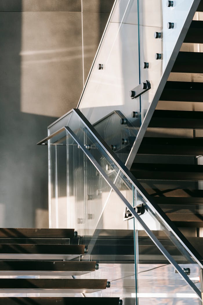 A modern glass staircase with metal accents in a sunlit interior setting.