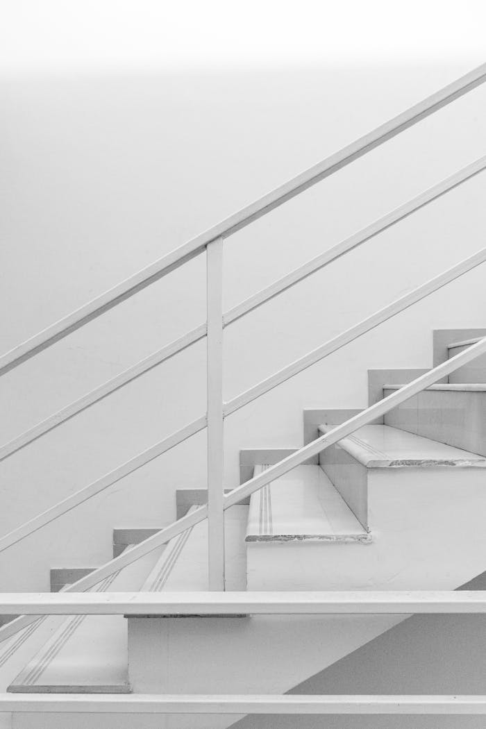 A clean and modern white staircase with metal railing in a minimalist setting.
